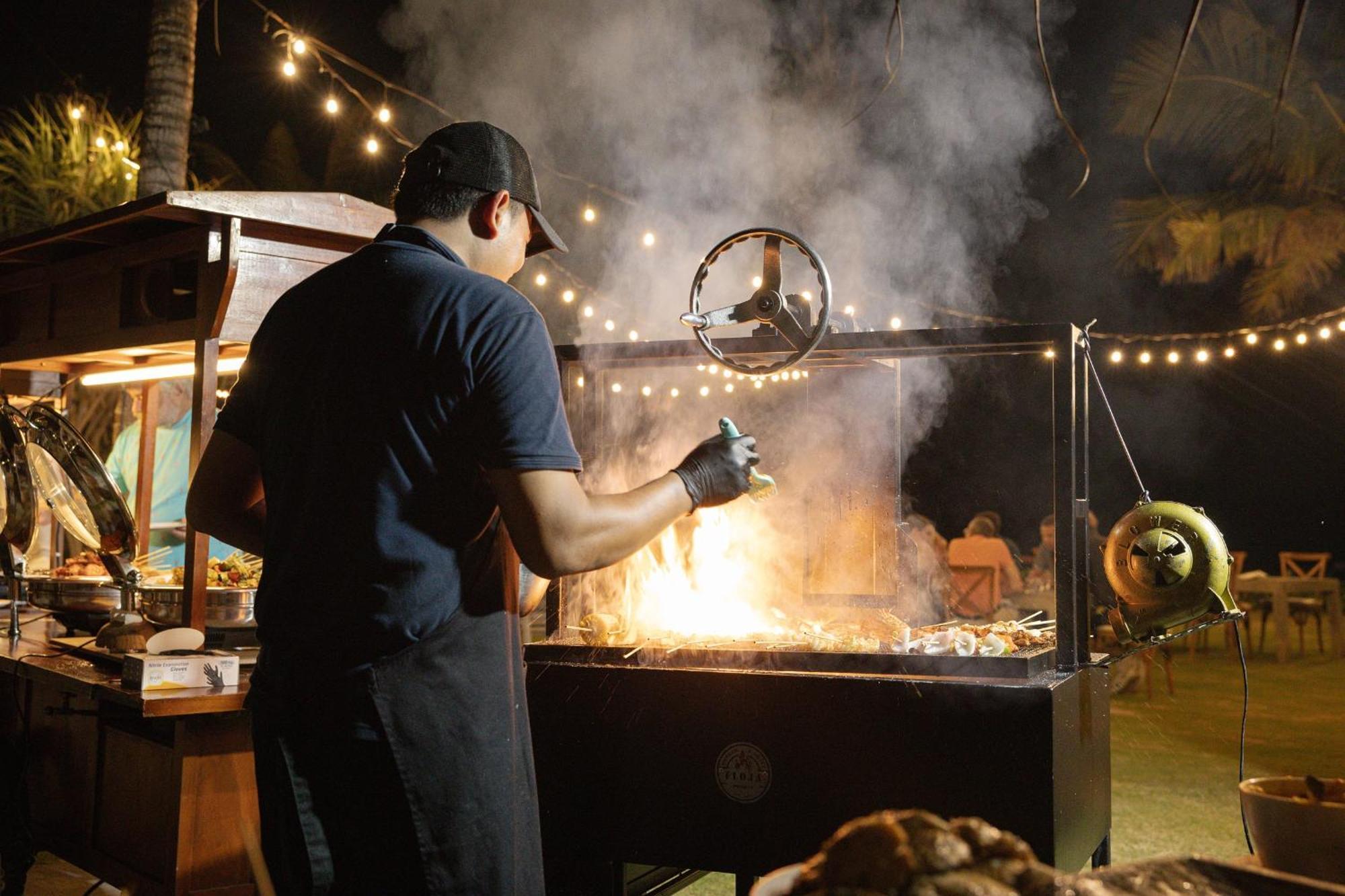 赛达拉精品海滩度假村 努沙杜瓦 外观 照片 A chef cooking over a wood-burning grill